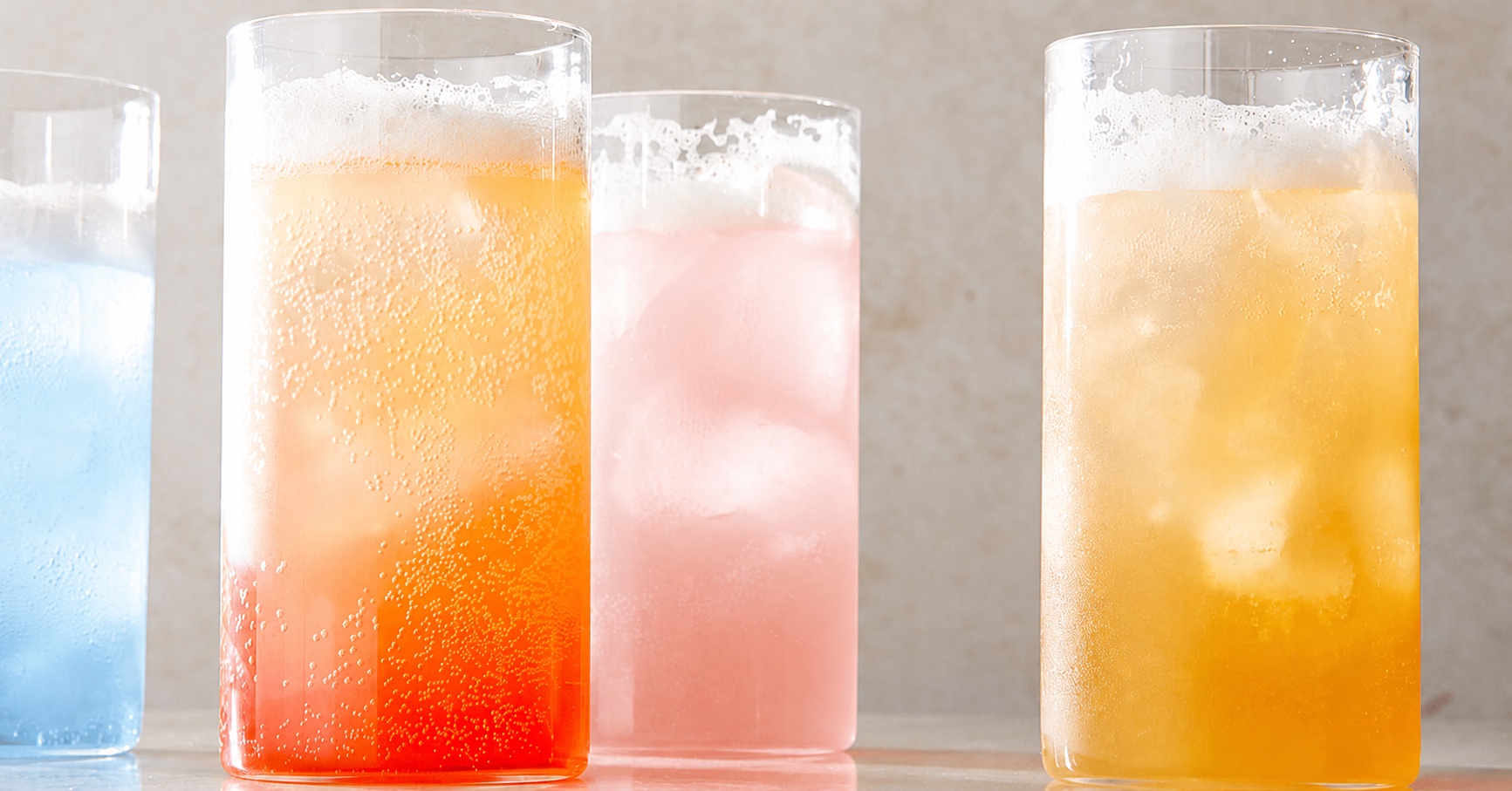 Four Flow & Soda serves over ice in light blue, orange, pale pink and golden tones